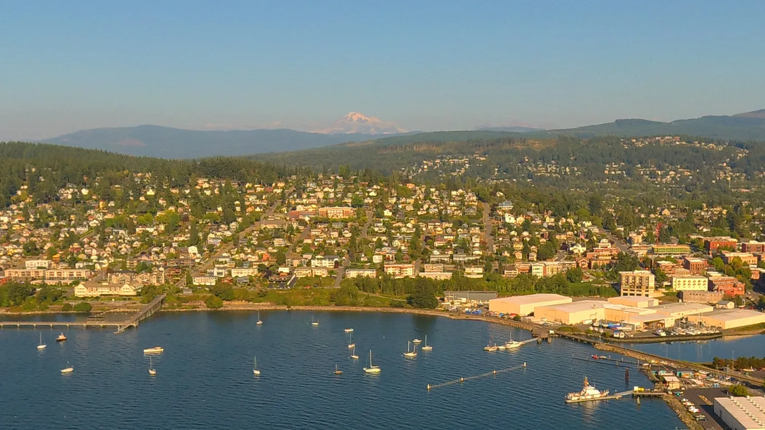 An aerial view of Bellingham, Washington, with sailboats on the bay and Mount Baker in the distance